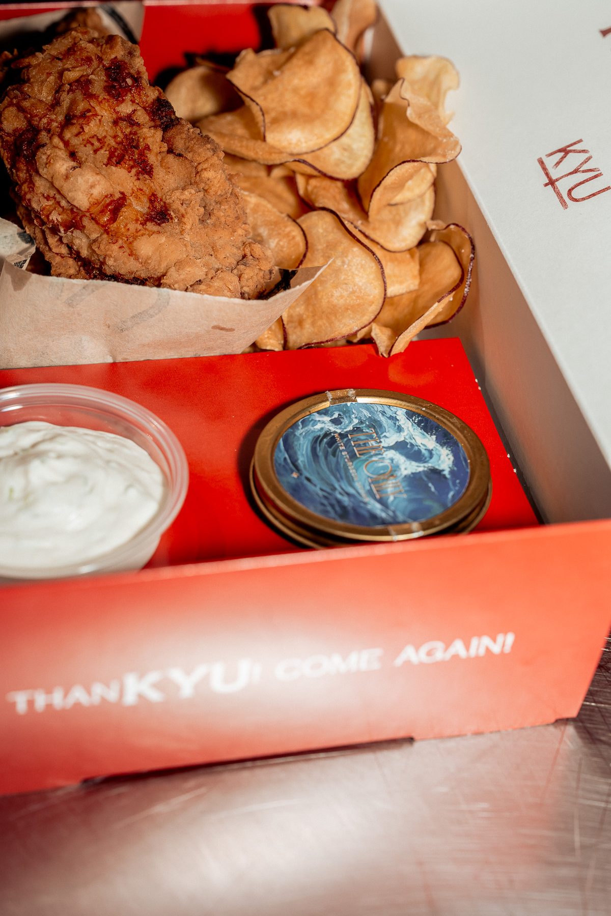 The ThanKYU box packed with fried chicken, chips, a tin of caviar and a cup of dip