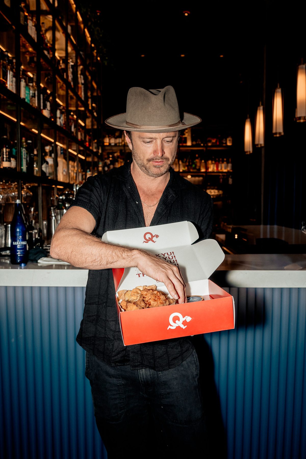 Aaron Paul opening a red ThanKYU box at the KYU bar