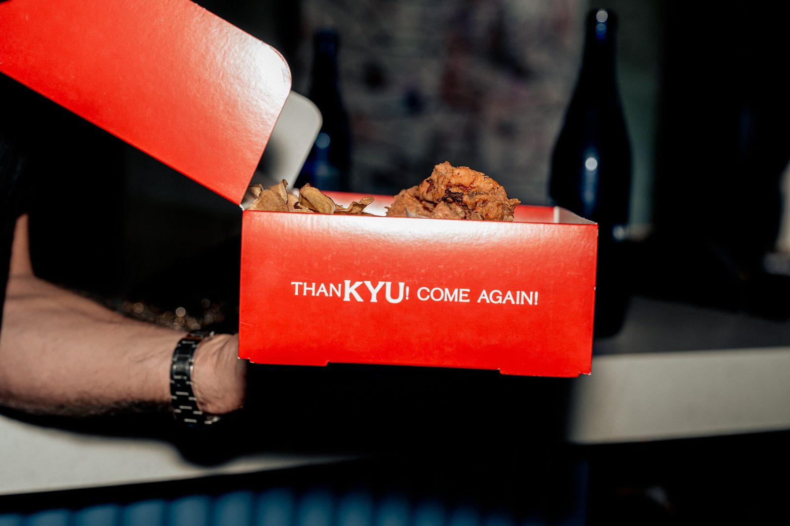 A hand passing the red ThanKYU box across the counter
