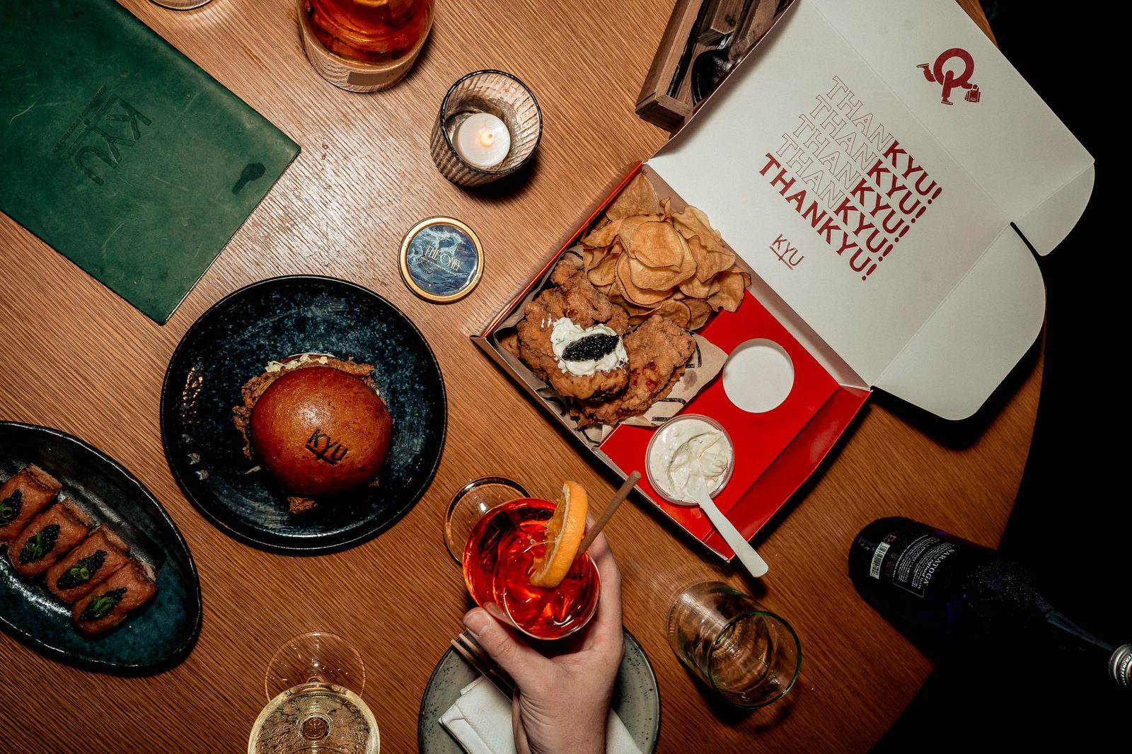 Overhead of the table spread with a hand reaching in beside cocktails and the open box