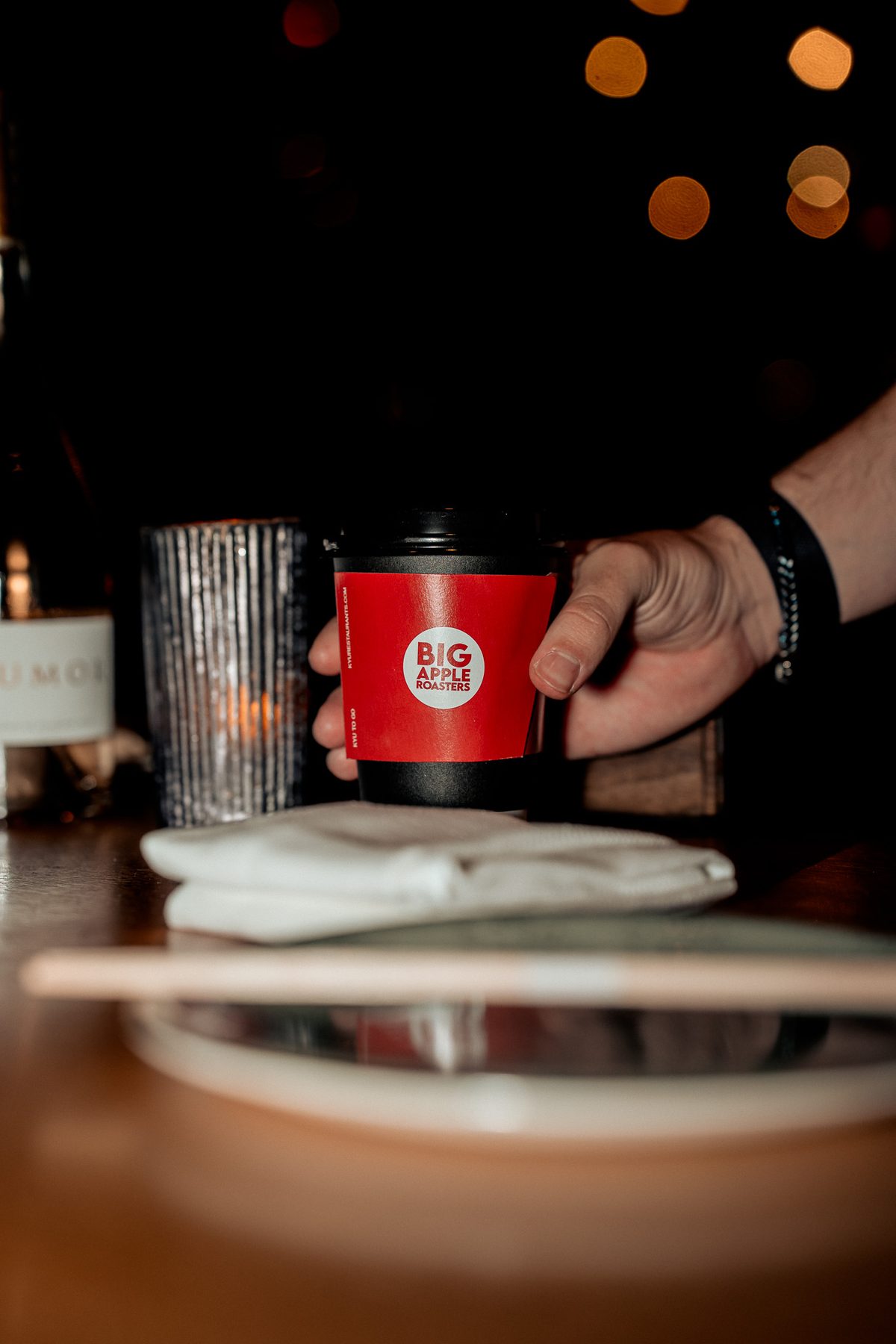 A red coffee cup set down on the bar in warm low light